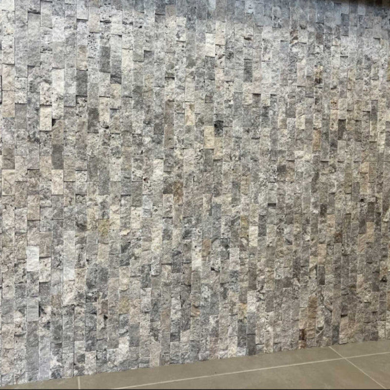 Wall made of small stone tiles in various shades of gray silver 1x2 split face