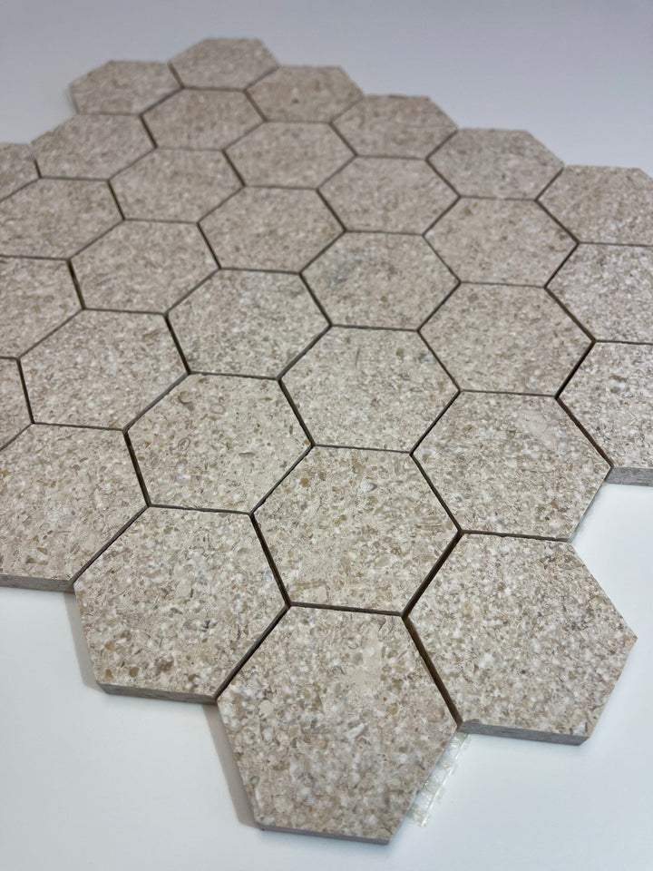 Gascogne Beige 2x2 hexagon tumbled limestone mosaic tile from TILE AND MOSAIC DEPOT, showing natural beige stone with textured surface.