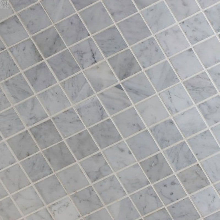 White Carrara marble 2x2 honed mosaic tile showing polished square tiles with natural gray veining for elegant surface design.